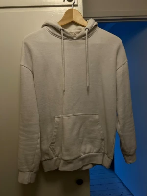 Beige hoodie från Pier One - En stilren beige hoodie från Pier One med klassisk känguruficka och justerbar huva med dragsko. Tillverkad i mjukt bomullsmaterial som känns skönt mot huden. Perfekt för en avslappnad look och enkel att matcha med jeans eller joggers.