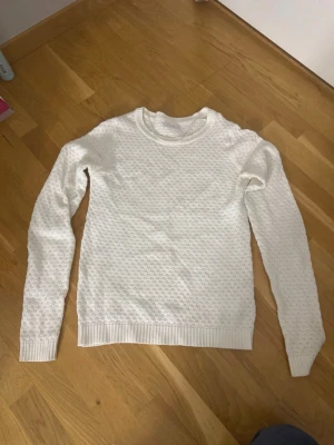 Vit stickad tröja med strukturmönster - Säljer en vit stickad tröja med diskret strukturmönster och rund hals. Lämna gärna prisförslag!