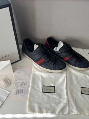 Gucci Ace i helt okej skick - Mörka Gucci ace i ganska bra skick. Storlek 46. Kommer med box, dustbags, kvitto (alla tillbehör du ser i bilden.  Kan gå ner i pris vid snabb affär