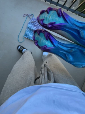 Nike Mercurial grå/lila fotbollsskor - Säljer ett par Nike Mercurial fotbollsskor i grått med lila och blå detaljer. Skorna har en strömlinjeformad design, stickad ovandel och en sula i blått och lila med aggressivt mönster för bra grepp. Perfekta för snabba spelare som vill sticka ut på planen.