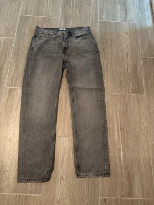 Grå raka jeans från 157 - Säljer ett par grå jeans från 157 med rak passform och klassisk femficksdesign. Jeansen har en diskret tvättad look och är tillverkade i denim. Perfekta för en avslappnad och stilren outfit.