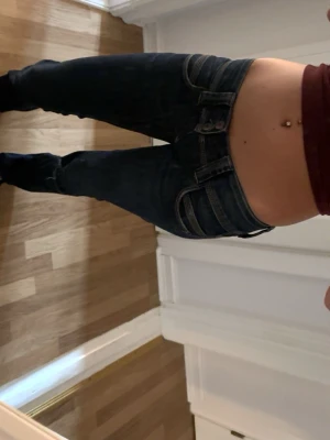 Mörkblå pepe jeans jeans bootcut - Säljer ett par mörkblå bootcut jeans från pepe jeans med klassiska fickor och snygga kontrastsömmar. Jeansen har låg midja och är tillverkade i denim med stretch för en bekväm passform. Perfekta för dig som gillar en tidlös och cool stil.