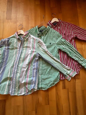 Randiga skjortor från Ralph Lauren - Tre långärmade skjortor från Ralph Lauren i olika färger och breda ränder. Endast använda ett få antal gånger, därav utmärkt skick. Storleken är ungdom Large, vilket är jämförbart med vuxen extra small. Styck pris 200kr men vid köp av alla tre 500kr. Tveka inte att ställa frågor.