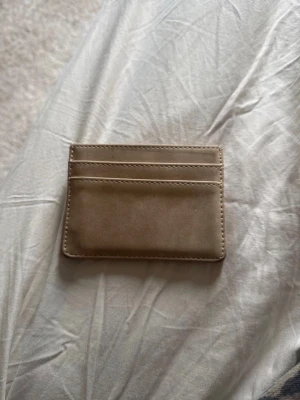 Beige kortfodral i skinn - Stilrent och smidigt kortfodral i beige skinn med plats för flera kort på båda sidor. Perfekt för dig som vill ha ett minimalistiskt och snyggt alternativ till plånbok. Enkel design utan synligt märke.