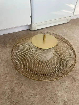 Guldig lampskärm i metallnät - Snygg lampskärm i guldigt metallnät med rund form och stilren design. Perfekt för att ge rummet en modern och trendig känsla. Passar till taklampa och har ett hål för montering av sladd eller sockel.