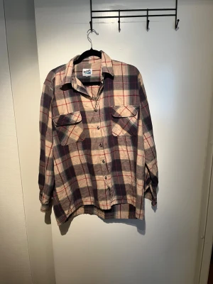 Rutig skjorta från Pacific Trail - Rutig skjorta i beige, vinrött och blått från Pacific Trail. Skjortan har två bröstfickor med lock, klassisk krage och knäppning framtill. Perfekt för en avslappnad och cool stil. Väldigt Avicii grisch som passar för den unga trenden laidback