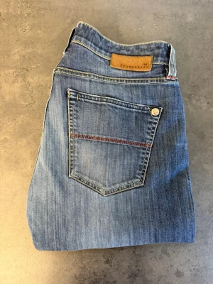 Blå jeans från Tramarossa W33 - Snygga blå jeans från True Religion med klassisk femficksdesign och raka ben. Jeansen har kontrastsömmar, läderpatch bak och diskret slitning framtill. Perfekta för en avslappnad och trendig look. Skriv för mått!