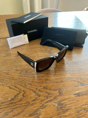 Chanel solglasögon - Black sunglasses from Chanel with gold details. Comes with everything included when purchased. Cleaning tissue, box, protective sunglass case etc.   I also have the receipt which I’ll send when purchased. I can also send a picture of it in the chat.  Retail price: 4750SEK/ 505$ USD   The sunglasses have only been used 2 or 3 times and are in great condition.