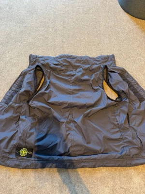 Mörk blå/ marin vindbreaker väst från Stone Island - Mörk blå/ marin vindbreaker väst från Stone Island med klassisk logotyp-patch nertill. Västen är tillverkad i lätt meshfoder på insidan för extra komfort. streetwear-stil. Ny pris 5000kr. (Pris kan diskuteras)