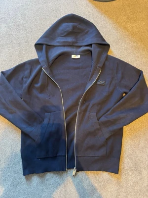 Mörkblå/ marin  zip hoodie från sandro  - Mörkblå/ marin  hoodie med dragkedja från Sandro. Klassisk modell med huva, två fickor fram och diskret logga på bröstet. Tillverkad i mjukt bomullsmaterial. Daily wear. (Pris kan diskuteras) ny pris 3500kr
