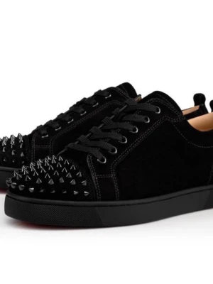 Svarta sneakers med nitar från Louboutin - Svarta sneakers i mocka från Christian Louboutin med coola svarta nitar på tån och klassisk röd sula. Skorna har svarta skosnören och en låg siluett som ger en edgy vibe. Perfekta för dig som vill sticka ut med din stil.