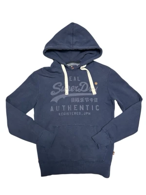 Superdry Vintage Hoodie - Klassisk hoodie från Superdry. Välanvänd och tvättad genom åren men fortfarande i fint skick. Skicket är som på bilderna, den har tvättats ut lite och har fläckar från tvättningen som syns på bild 3, därutöver priset. OBS: Storleken är XS men passar som S, därför står det S i storlek. Skick: 7/10 Pris kan diskuteras 📦 Skickas eller möts upp