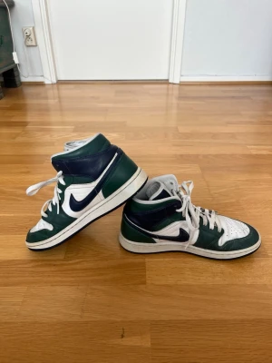Jordan Air 1 Mid Noble Green – Storlek 41 - Säljer ett par Air Jordan 1 Mid i riktigt snygg grön/vit/blå färgkombination. Skorna är använda men fortfarande i bra skick och sitter riktigt bra på foten. Perfekta både till vardag och till outfits. Storlek 41. Det finns en del gångveck vilket syns på bilderna, men inget som stör helhetsintrycket. Fortfarande mycket kvar att ge.