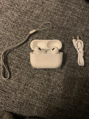 Vita trådlösa in-ear hörlurar - Säljer ett par vita trådlösa in-ear hörlurar med laddningsetui. Hörlurarna har en stilren och modern design med slät yta och svarta detaljer. Medföljer gör även en USB-laddningskabel och handledsrem. Perfekta för musik, poddar och samtal på språng. de är inte riktiga men den e nya och super bra