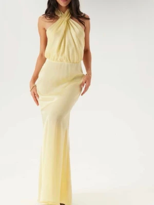 Ljusgul långklänning med halterneck - Elegant långklänning i ljusgul ton med halterneck och draperad överdel. Klänningen har en figurnära passform över höfterna och ett mjukt, flytande fall. Perfekt för speciella tillfällen där du vill sticka ut med en stilren look. Använd och tvättad en gång. Nypris 1300kr 