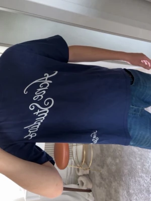 Mörkblå Ace Studios t-shirt - Säljer en mörkblå t-shirt från Ace Studios med vit text i snyggt typsnitt på bröstet och en mindre logga vid nederkanten. T-shirten har normal passform och är tillverkad i mjuk bomull. Perfekt till jeans eller shorts för en clean look.