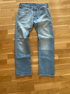 Levi's ljusblå raka jeans - Klassiska ljusblå jeans från Levi's med rak passform och fem fickor. Jeansen har en vintage tvätt och är tillverkade i slitstark denim. Perfekta för en avslappnad och tidlös stil. Levi's patch bak i midjan och röda etiketten på bakfickan.