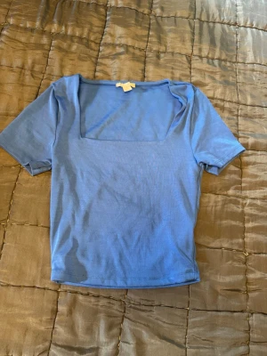 T-shirt  - Säljer en fin blå kort T-shirt med fin urringning. Storlek L men sitter som en M 