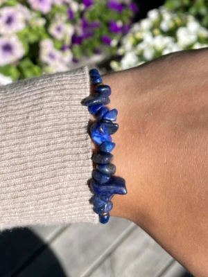 Blått armband med oregelbundna pärlor - Snyggt armband med djupblå oregelbundna pärlor och små guldfärgade detaljer. Armbandet har justerbar knytning och är gjort av stenar och pärlor i olika former. Perfekt accessoar för dig som gillar unika smycken och vill sticka ut.