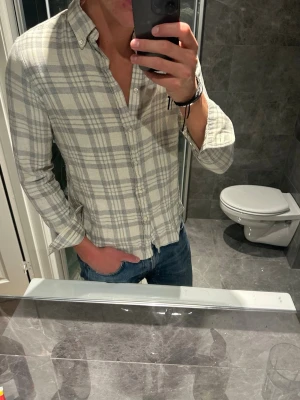 Ljusrutig skjorta med knappar - Säljer nu en riktigt snygg rutig skjorta i vitt och ljusgrått från Ralph Lauren. Skjortan är i bra skick bortsett från att den krympt något i tvätten. Ursprungligen var det en M men sitter nu mer som en S. Hör av er vid fler frågor ;)