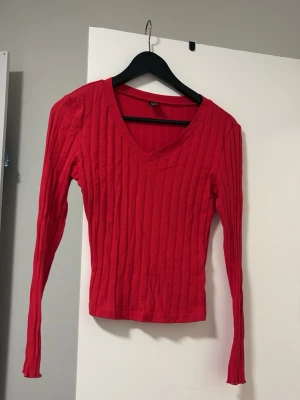 Röd ribbstickad tröja V-ringad - Snygg röd ribbstickad tröja från Bik Bok med V-ringning och långa ärmar. Tröjan har en figurnära passform och är perfekt för att addera färg till din outfit. Materialet är mjukt och stretchigt för extra komfort.