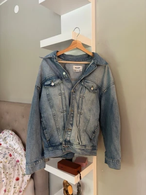 Oversized ljusblå jeansjacka Weekday - Säljer en oversized ljusblå jeansjacka från Weekday. Klassisk modell med två bröstfickor med lock och knappar, samt knappstängning framtill. Snygga sömdetaljer och avslappnad passform. Perfekt att slänga över en hoodie eller t-shirt.