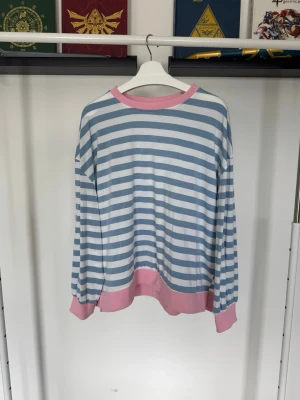 Randig t-shirt med rosa krage - Snygg t-shirt med breda blå och vita ränder och en kontrasterande rosa krage. Oversized.