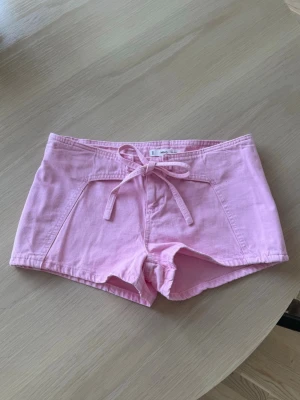 ljus Rosa Lågmidjade shorts med rosett - Säljer ett par ljusrosa Lågmidjade shorts från Mango i mjuk bomull. Shortsen har en snygg knytning framtill och kort passform. Perfekta till varma dagar och enkla att matcha med crop tops eller linnen.                                   Helt nya med prislappen kvar!!‼️