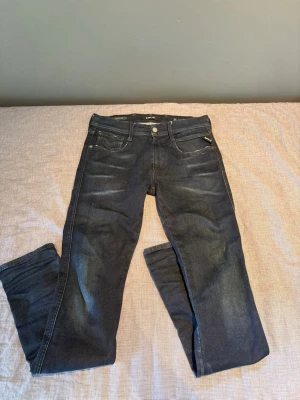 Replay Anbass - Snygga mörkblå slim fit jeans med klassisk femficksdesign och dragkedja i myntfickan. Jeansen har subtila slitningar framtill och raka ben. Perfekta för en avslappnad och trendig look.