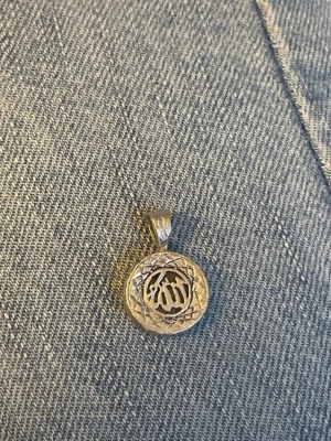 Silverhalsband med arabisk text - Säljer ett runt hängsmycke i äkta silver (925) med ett detaljerat mönster och arabisk text i mitten. Hängsmycket har en snygg ram och är perfekt för dig som gillar unika smycken med betydelsefulla symboler.