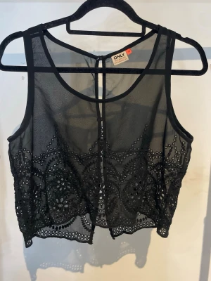 Svart topp - En svart genomskinlig topp från Only, storlek 36.