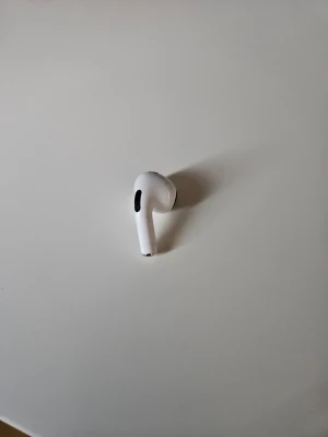 Air pod 3 höger öra - Snygg vit trådlös in-ear hörlur med stilren design och svarta detaljer. Hörluren har en kompakt form och är tillverkad i plast, perfekt för dig som gillar minimalistisk teknik och smidig användning. Kan diskuters om priset