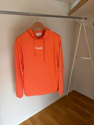 Orange hoodie med tryck - Snygg orange hoodie med huva och dragsko. På bröstet finns ett vitt tryck med texten 'Originals'. Hoodien har långa ärmar och är tillverkad i mjukt material, perfekt för en avslappnad stil.