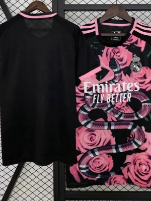 Real Madrid x Adidas rosa matchtröja - Unik Real Madrid matchtröja från Adidas med rosa rosor och ormtryck på framsidan. Svart bas med rosa detaljer och klubbmärke på bröstet. Tillverkad i lätt och ventilerande material, perfekt för fotboll eller streetwear.