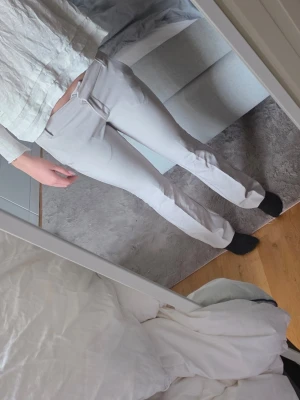 Beiga  kostymbyxor med raka ben - Säljer ett par stilrena beiga kostymbyxor . Byxorna har hög midja, bälteshällor och diskreta fickor fram. Perfekta för en clean och modern look. Materialet känns mjukt och följsamt, troligtvis en blandning av polyester och viskos.