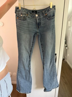 Ljusblå bootcut jeans med fickdetaljer - Säljer ett par ljusblå bootcut jeans med snygga fickdetaljer både fram och bak. väldigt fint skick. original pris är 1599kr. storlek 28