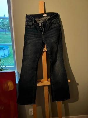 Mörkblå bootcut jeans från Nelly - Snygga mörkblå bootcut jeans från Nelly med deras ikoniska fickor och dubbla knappar i midjan. Jeansen har en lätt utsvängd passform och kontrastsömmar. Perfekta för dig som gillar en tidlös och trendig look. Super bekväma och passar till nästan allt💕