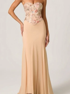Långklänning med corset  - Elegant axelbandslös långklänning i champagnefärg/rosa  med blommig spets corset upptill i pastelltoner. Klänningen har en figurnära passform upptill och faller mjukt från midjan. Perfekt för speciella tillfällen.