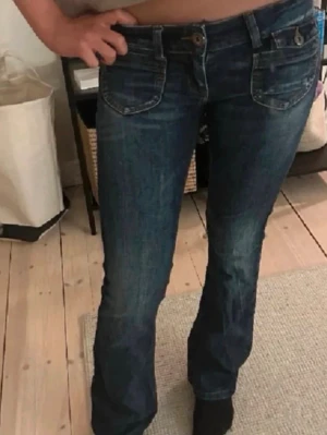 Mörkblå low waist bootcut jeans med fickor i fram💕 - SÅ snygga low waist bootcut jeans 🤍  Perfekt fit som sitter tight över höfter & rumpa och blir lite utsvängda nertill 😍 ger verkligen den där Y2K-viben  Fint skick + sköna med stretch   Passar till allt!!  Säljer pga används inte 💔  Strl: W27 L32