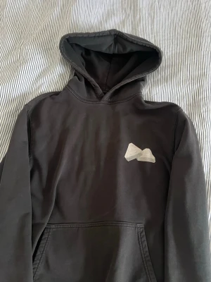 Svart hoodie från Palace med tryck - Säljer en svart hoodie från Palace med en liten logga på bröstet och ett stort, färgstarkt tryck på ryggen. Perfekt för dig som gillar streetwear och unika prints. 