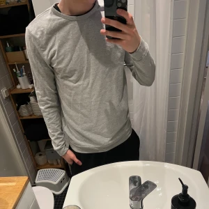 Ljusgrå långärmad tröja Samsøe Samsøe - Säljer en stilren ljusgrå långärmad tröja från Samsøe Samsøe. Tröjan har en enkel och clean design med rund halsringning och mjukt material som känns skönt mot huden. Perfekt basplagg för alla tillfällen.