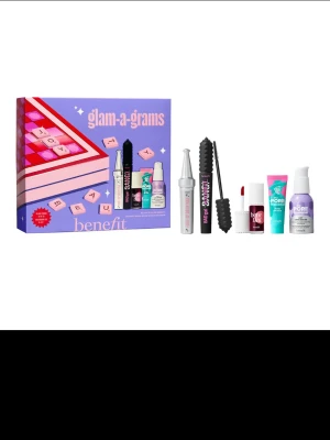 Benefit glam-a-grams presentkit - Snyggt presentkit från Benefit med fem populära skönhetsprodukter i miniformat. Innehåller mascara, bryngel, primer, ansiktskräm och läpp- & kindtint. Förpackningen är lila och rosa med scrabble-inspirerad design. Perfekt för dig som vill testa flera produkter från Benefit.