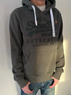 Mörkgrå hoodie från Superdry - Snygg mörkgrå hoodie från Superdry, skriv vid minsta fundering!