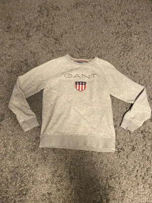 Grå Gant tjocktröja - Storlek:158-164 cm, i fin kvalitet och inköpt från kids brand store online.