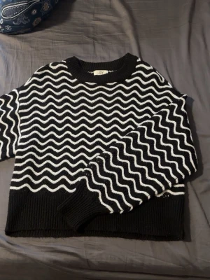 Svartvitt stickad tröja från JDY - Stickad tröja från JDY/Only i svart med vita vågmönster över hela plagget. Storlek XS