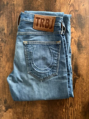 True Religion Jeans - True Religion jeans i storlek 29. Snygg tvätt med naturlig fade och slitningar som ger en clean casual look. Byxorna är i bra skick överlag, inga större defekter. Observera att de är klippta längst ner vilket ger en rå kant. Perfekta för street/casual fits.