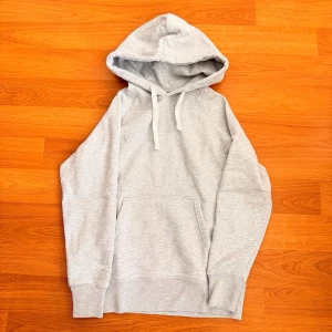 Russemerch hoodie med huva - Snygg ljusgrå hoodie från Russemerch med klassisk känguruficka och dragsko i huvan. Tillverkad i mjukt material som känns skönt mot huden. Perfekt för en avslappnad och stilren look.