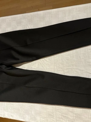 Svart set från Les Deux - Snygg svart ziptröja och byxor från Les Deux med hög krage och dragkedja framtill. Tröjan har ribbade muddar vid ärmslut och nederkant samt diskret logga på bröstet. Tillverkad i ett mjukt och stretchigt material som passar perfekt till en avslappnad stil.