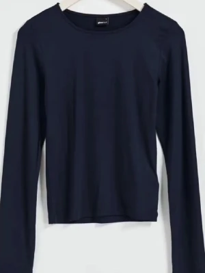 Mörkblå långärmad topp Gina Tricot - En enkel och stilren mörkblå långärmad topp från Gina Tricot. Modellen har rund halsringning och är figurnära i passformen. Perfekt att matcha med jeans eller kjol för en clean look.