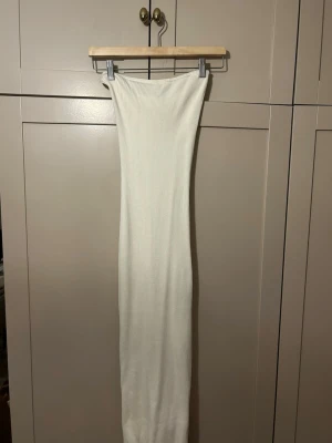 vit ribbad långklänning H&M - säljer en lång, ribbad klänning från H&M i vit färg. Klänningen har en smal passform och är tillverkad i ett stretchigt material som sitter snyggt på kroppen. Perfekt för dig som gillar minimalistisk och stilren look. 